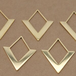 May include: Five gold-coloured geometric earring components. Each component features a diamond shape with a V-shaped extension at the bottom. The earrings are displayed on a neutral brown surface.