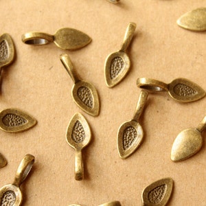 Peut inclure: Un groupe de 18 embouts de pendentif en métal doré avec un motif en forme de feuille. Les embouts ont une petite boucle en haut pour les attacher à des bijoux.