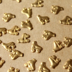 May include: A close-up of a brown surface covered with gold-coloured roller skate charms. The charms are scattered randomly across the surface.