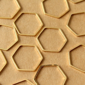 May include: A collection of gold-colored metal hexagonal rings arranged in a honeycomb pattern on a brown surface.