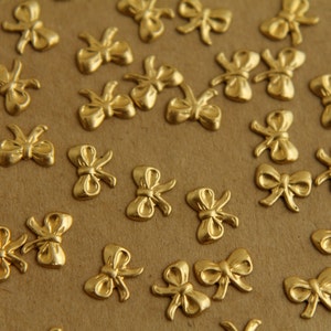 Op de afbeelding: Een close-up van een bruin oppervlak bedekt met gouden metalen strikversieringen. De strikken zijn willekeurig over het oppervlak verspreid.