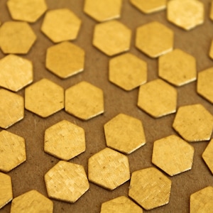 May include: A close-up of a surface covered in gold hexagonal metal pieces. The pieces are arranged in a honeycomb pattern.