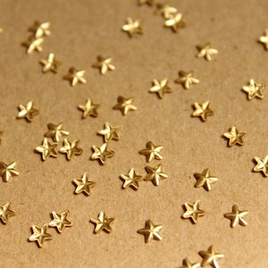 Puede incluir: Primer plano de una superficie marrón cubierta con adornos dorados en forma de estrella.