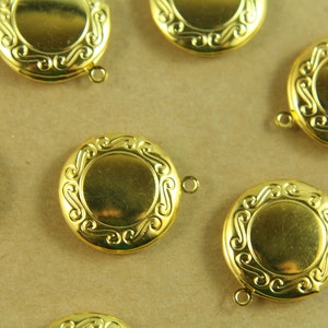 May include: Six gold-toned metal locket charms with ornate designs. Each charm has a circular shape with a raised rim and a decorative border. The charms have a loop at the top for attaching to a necklace or bracelet.