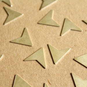 May include: A close-up of a brown surface with multiple gold-coloured arrow shapes scattered across it.