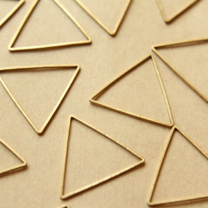 May include: A close-up of a group of gold triangle shapes on a brown background. The triangles are all the same size and shape, and they are arranged in a random pattern.