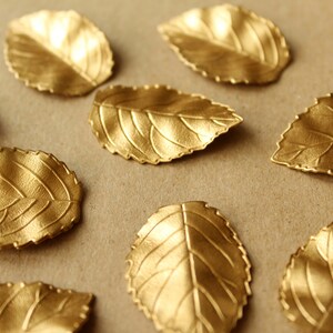 May include: A collection of gold-painted leaf-shaped decorations on a brown background.