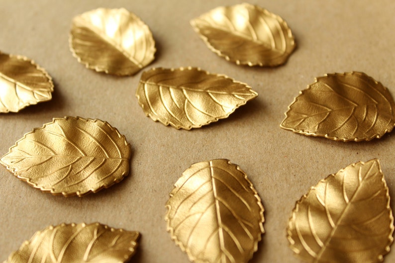 May include: A collection of gold-painted leaf-shaped decorations on a brown background.