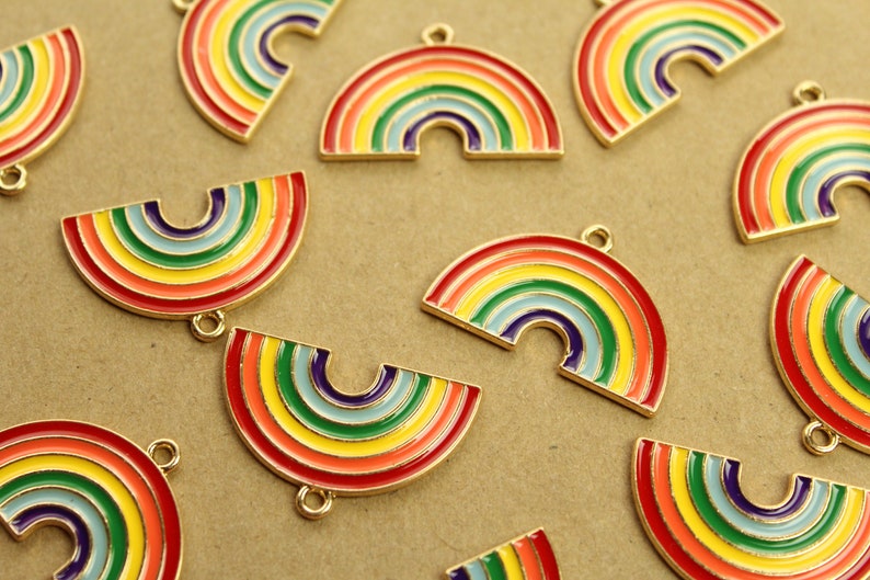 Peut inclure: Un ensemble de breloques arc-en-ciel dor&eacute;es avec une finition &eacute;maill&eacute;e color&eacute;e. Les breloques sont en forme de demi-cercles et d'arches compl&egrave;tes, et elles ont une boucle en haut pour &ecirc;tre attach&eacute;es &agrave; des bijoux ou d'autres objets artisanaux.