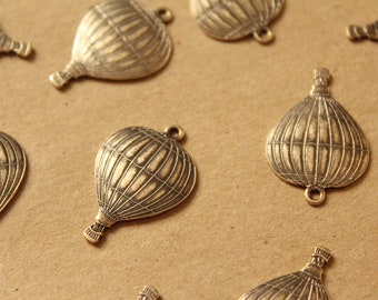 May include: A collection of antique gold-toned metal hot air balloon charms. The charms are detailed with a textured surface and have a loop for hanging.