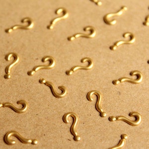 Könnte beinhalten: Nahaufnahme einer braunen Oberfläche mit vielen goldenen Fragezeichen, die darauf verstreut sind.