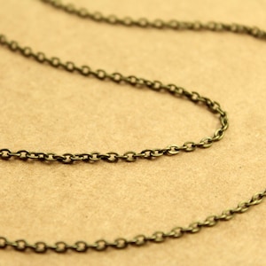 May include: A close-up of a bronze chain necklace. The chain is made of small, linked oval shapes.