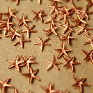 May include: A scattering of copper-colored starfish on a brown surface. The starfish are all different sizes and shapes, but they are all made of the same material.
