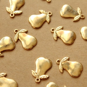May include: A collection of gold-toned metal pear charms with leaf accents. The charms are scattered on a brown surface.