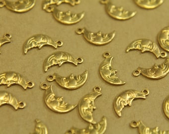 May include: A collection of gold-toned metal charms shaped like crescent moons with a face on each. The charms have a hole at the top for attaching to a necklace or bracelet.