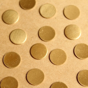 May include: A close-up of a brown surface covered with many small, round, gold-colored metal discs.