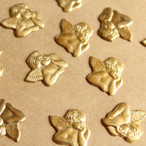 May include: A collection of gold-colored angel figurines with wings, each with a different pose. The angels are all facing forward and have their heads tilted slightly to the side. They are all made of a smooth, shiny material.