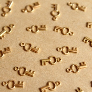 May include: A close-up of a brown surface with many gold-colored key charms scattered across it. The keys are all the same design, with a round loop at the top and a small keyhole.