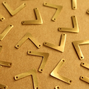 May include: A collection of gold-coloured metal corner brackets, arranged in a scattered pattern on a brown surface.