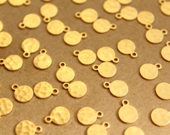 May include: A collection of gold-toned metal round charms with a hammered texture and a loop for attaching to jewelry or other crafts.