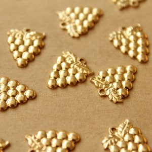 May include: A collection of gold-toned metal grape charms. Each charm features a cluster of grapes with a detailed stem and leaves.