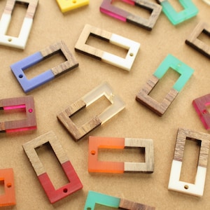 May include: Assortment of colorful rectangular wooden and resin pendant charms with a hole at the top for hanging. The charms are half wood and half resin, with a variety of colors including blue, green, pink, orange, and white.