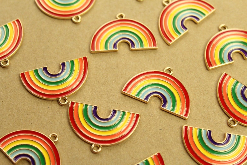 Peut inclure: Un groupe de breloques en m&eacute;tal en forme de demi-cercle, aux couleurs de l'arc-en-ciel. Les breloques ont une finition dor&eacute;e et sont parfaites pour ajouter une touche de fantaisie &agrave; des bijoux ou des objets artisanaux.
