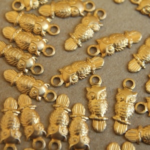 May include: A collection of gold-toned owl charms with intricate details. Each charm features a unique owl design with a loop for attaching to jewelry or other crafts.