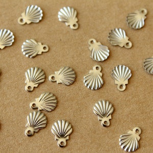 May include: A collection of silver-toned metal seashell charms with a loop at the top for attaching to jewelry or crafts.