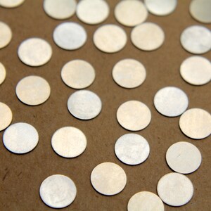 May include: A close-up of a brown surface covered with silver metallic confetti circles.