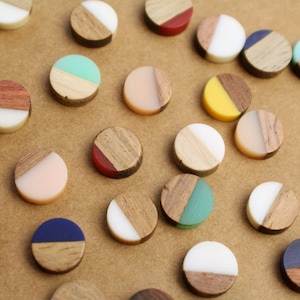 May include: Assortment of colorful, round, wooden and resin ornaments with a variety of colors and patterns. Each ornament is divided in half, with one half being wood and the other half being resin.