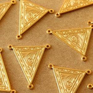Peut inclure: Dix breloques en métal de forme triangulaire dorées avec des motifs floraux complexes. Chaque breloque a trois trous pour l'attacher à des bijoux ou d'autres objets artisanaux.