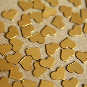 May include: A close-up of a brown surface covered with gold heart-shaped confetti.