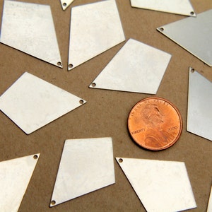 May include: A collection of silver-colored metal diamond-shaped charms with a hole at the top. The charms are scattered on a brown surface with a penny in the center.