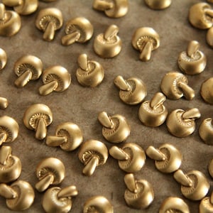 Puede incluir: Una colección de adornos de metal en forma de hongo de color dorado.