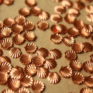 May include: A scattering of copper-colored seashell-shaped embellishments on a brown surface.