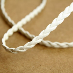 May include: White braided leather cord, close-up view of the texture and weave of the cord.