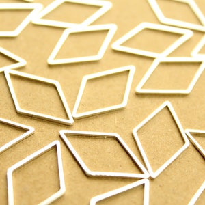 May include: A collection of silver-toned metal diamond shapes arranged in a pattern on a brown surface.