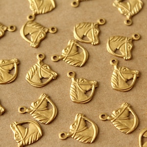 May include: A collection of gold-toned horse head charms with a detailed design. The charms have a loop at the top for attaching to jewelry or other crafts.