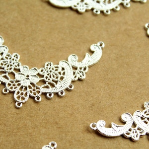 May include: Silver filigree embellishments with a delicate floral design. These decorative pieces are perfect for adding a touch of elegance to crafts and jewelry.