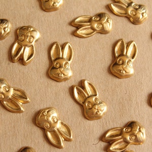Könnte beinhalten: Eine Sammlung von goldfarbenen Metall-Hasenanhängern mit einem detaillierten Design. Die Anhänger sind auf einer braunen Oberfläche angeordnet.