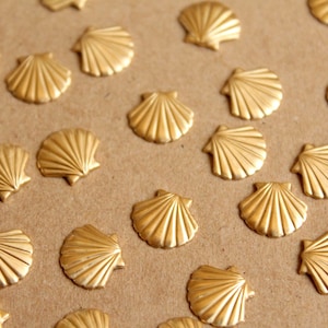 Könnte beinhalten: Eine Sammlung goldfarbener, muschelförmiger Dekoelemente auf einer braunen Oberfläche.