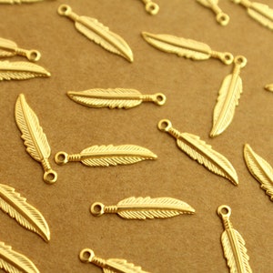 May include: A collection of gold-toned metal feather charms with a loop at the top for attaching to jewelry or other crafts.