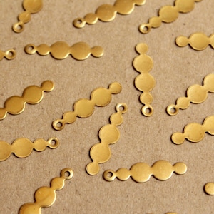 May include: A collection of gold-toned metal embellishments, each featuring a row of five rounded shapes. The embellishments have a hole at each end, suggesting they are designed for attaching to other items.
