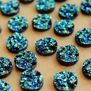 May include: A collection of round, iridescent blue and green agate slices. The slices are approximately 1 inch in diameter and have a natural, irregular shape.
