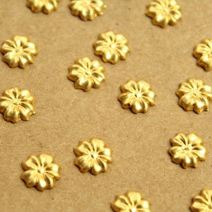 Puede incluir: Primer plano de una superficie marrón con muchos adornos dorados en forma de flor esparcidos por ella.