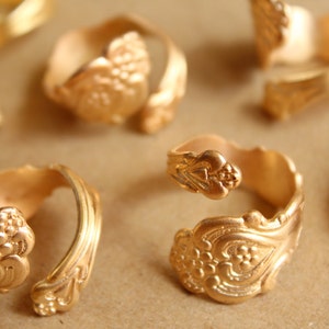 May include: A collection of gold-toned rings with intricate floral designs. The rings are made from recycled materials and are perfect for adding a touch of vintage style to any outfit.