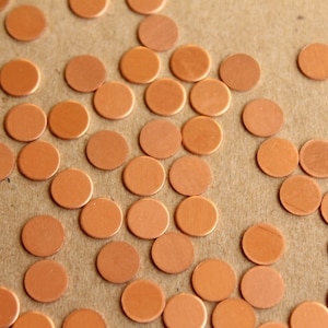 May include: A close-up of a brown background with many small, round, copper-colored discs scattered across the surface.