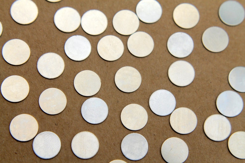 May include: A close-up of a brown surface covered with silver metallic confetti circles.