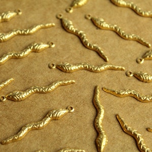 May include: A collection of gold-toned snake-shaped charms with a textured surface. The charms have a loop at the top for attaching to jewelry or other crafts.